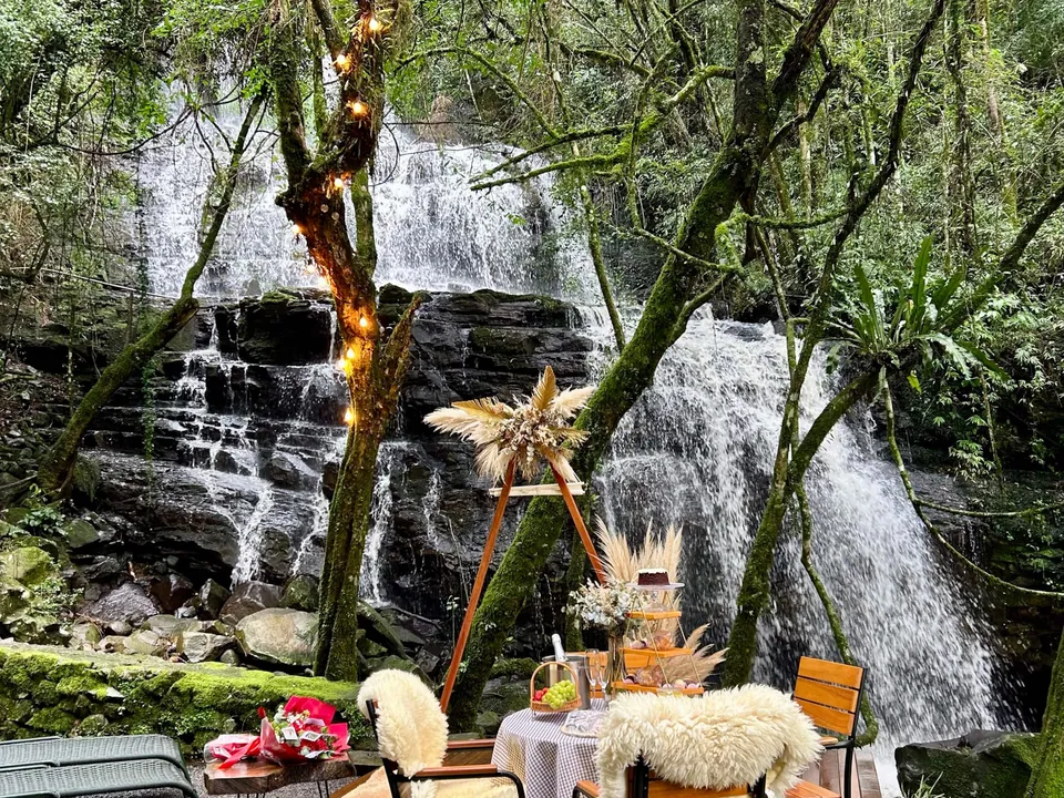 Mesa decorada com pelegos e flores secas no deck, diante da cascata