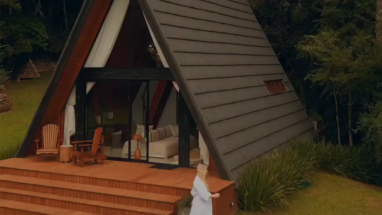 A cabana Lumine em A, com o deck, o gramado e a mata ao redor